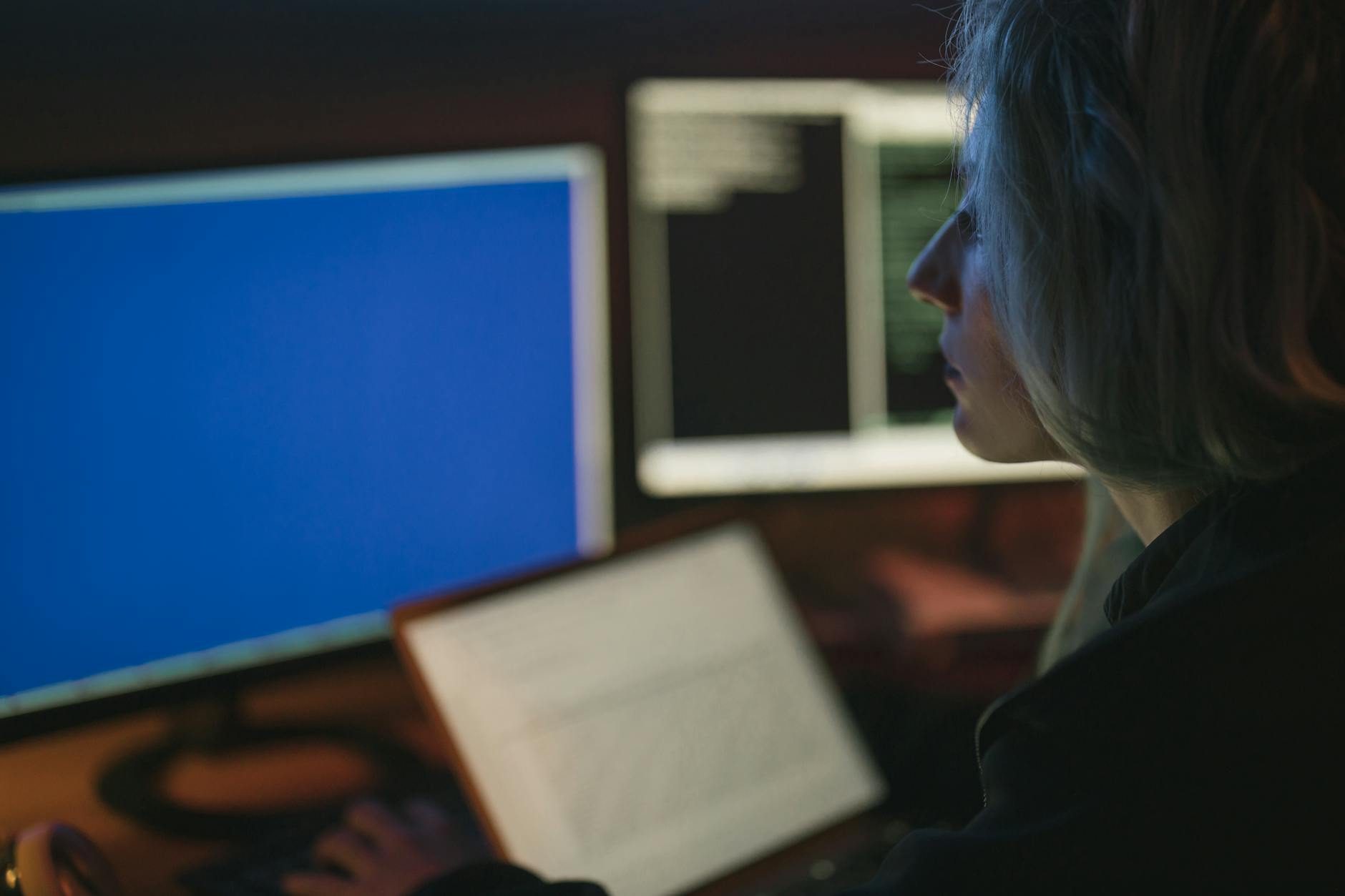 Kobieta pracująca nocą przy kilku monitorach z narzędziami bezpieczeństwa