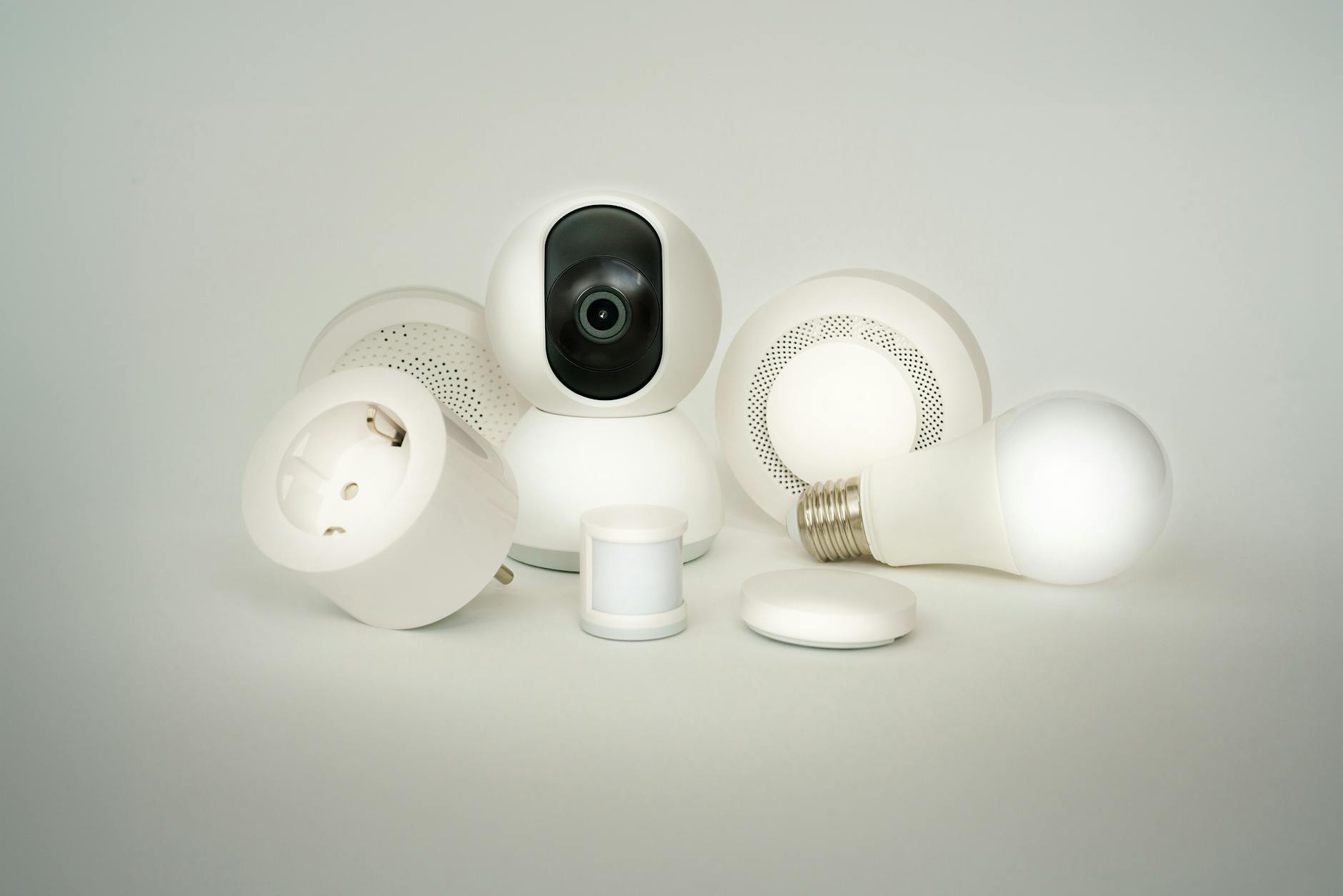 Różne urządzenia smart home na białym tle: żarówki, gniazdka, kamery