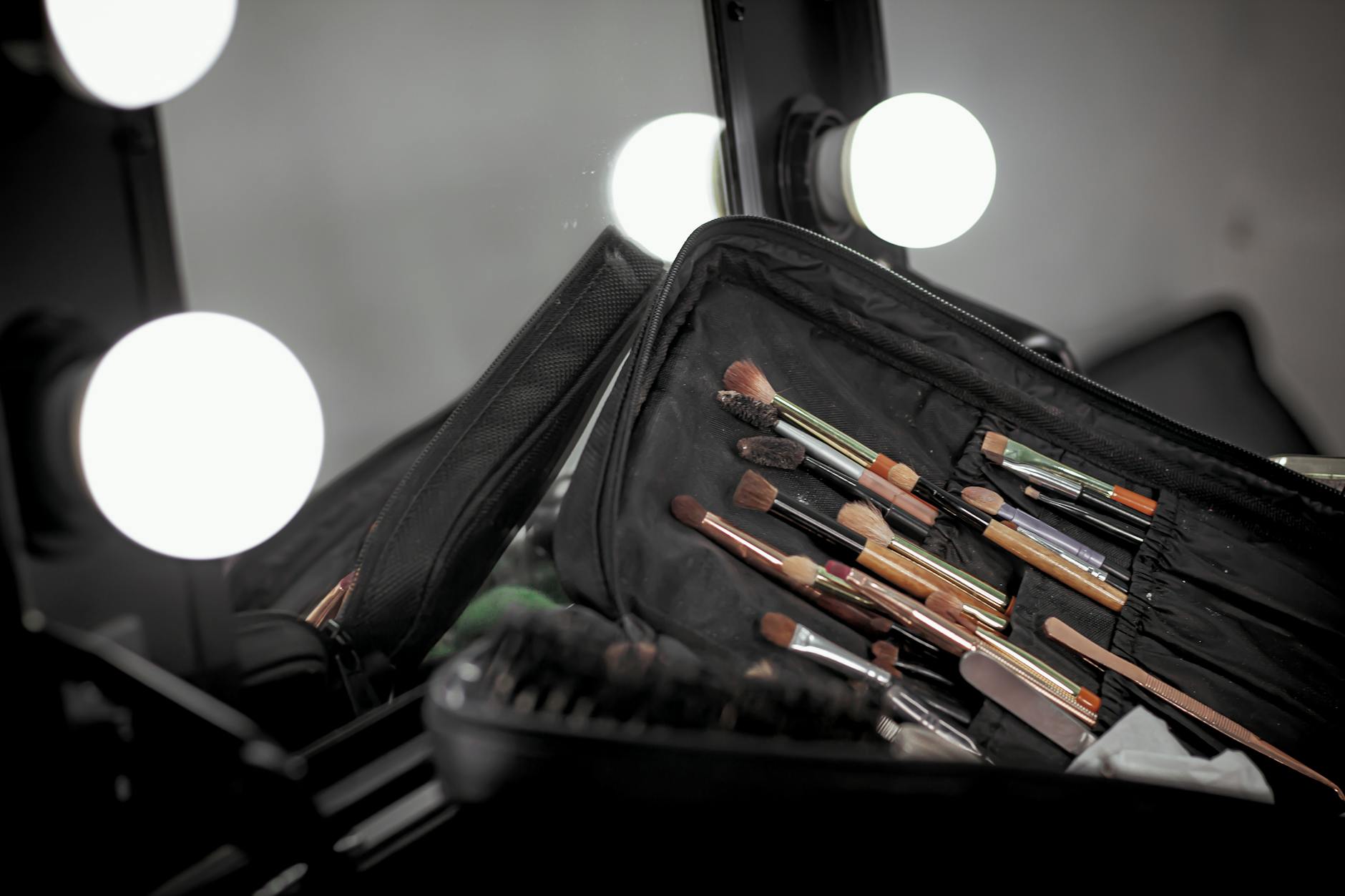 Zestaw pędzli do makijażu na toaletce oświetlonej lampami vanity