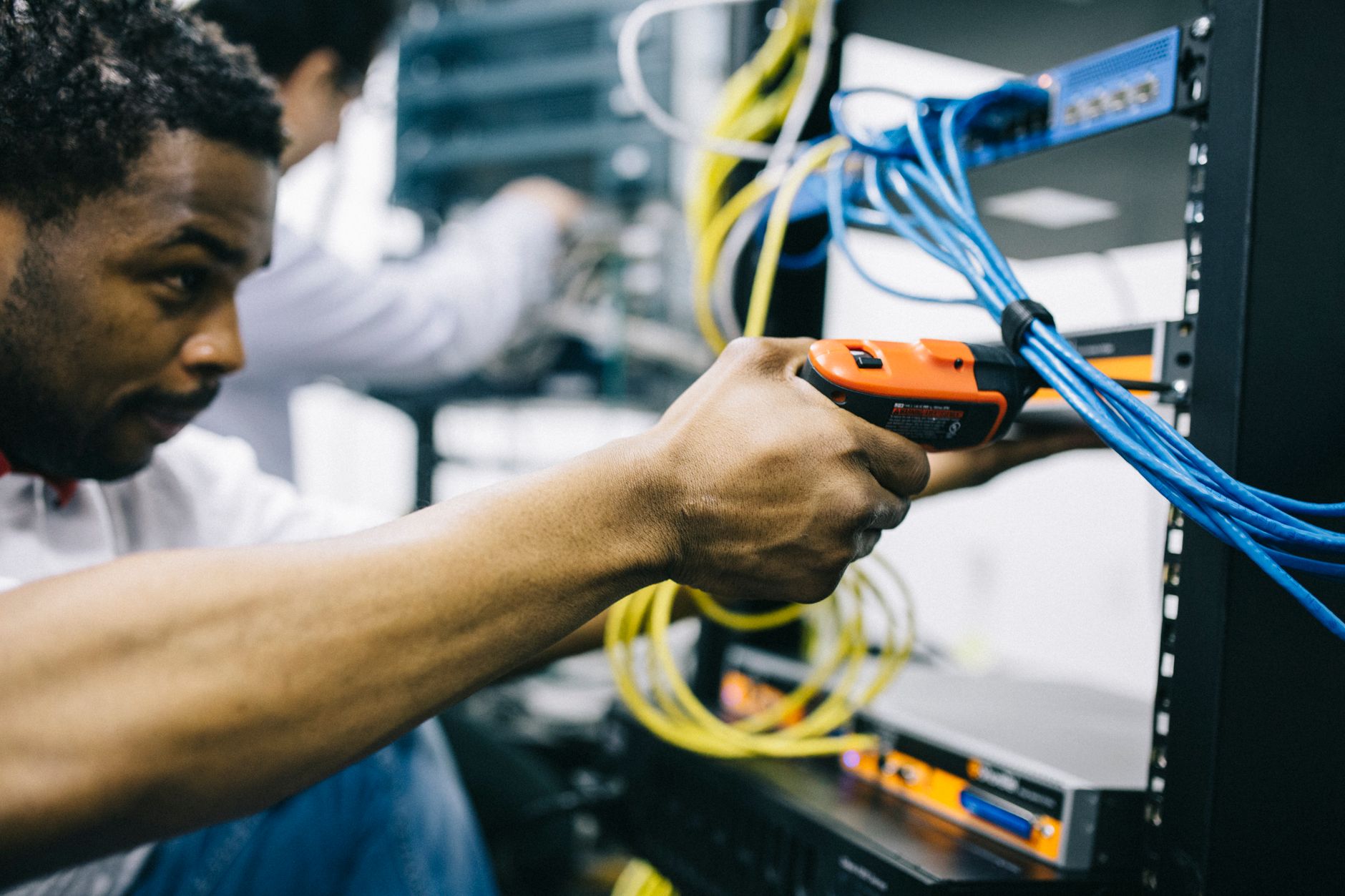 Inżynier serwisuje sprzęt sieciowy wkrętarką elektryczną