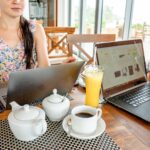 Kobieta pracująca zdalnie przy laptopach w kawiarni z herbatą