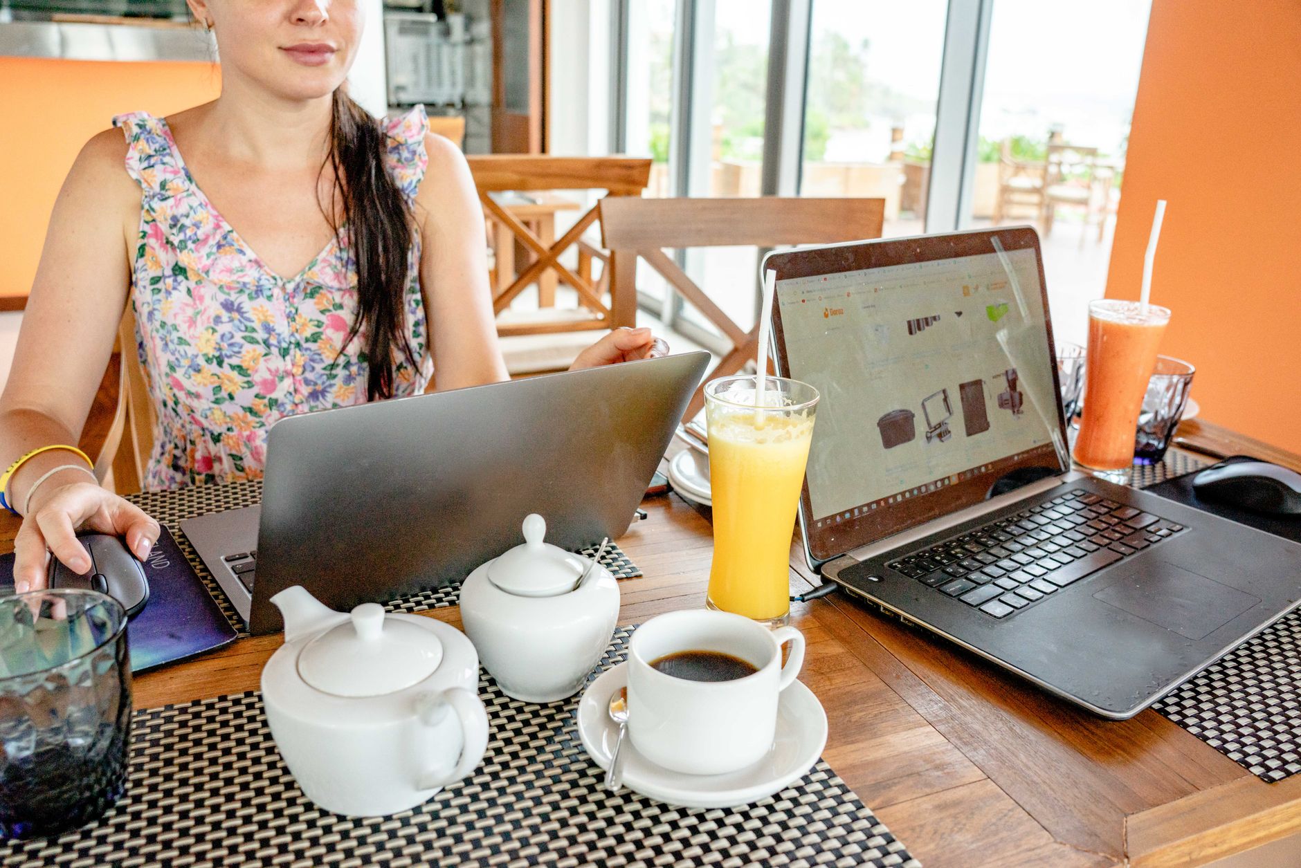 Kobieta pracująca zdalnie przy laptopach w kawiarni z herbatą