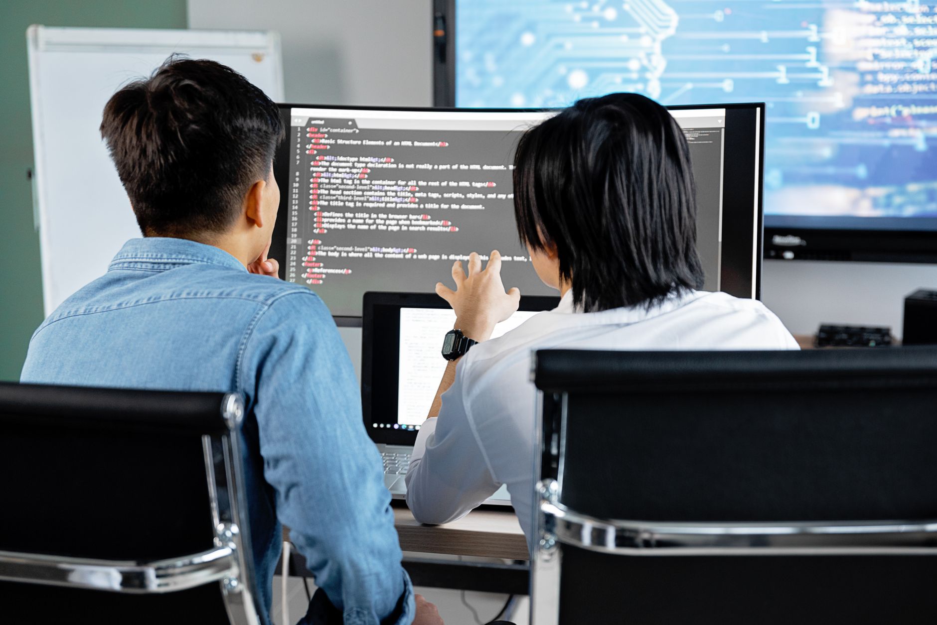 Dwóch programistów omawia kod na ekranie w biurze